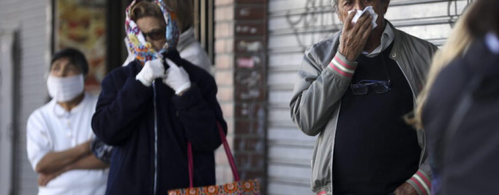 People, using different methods to cover their mouth and nose, wait in line outside a bank during a government-ordered lockdown to curb the spread of the new coronavirus, in Buenos Aires, Argentina, Saturday, April 4, 2020. The city banks are opening for the weekend so that retirees may pick up their monthly pension payment. (AP Photo/Natacha Pisarenko)